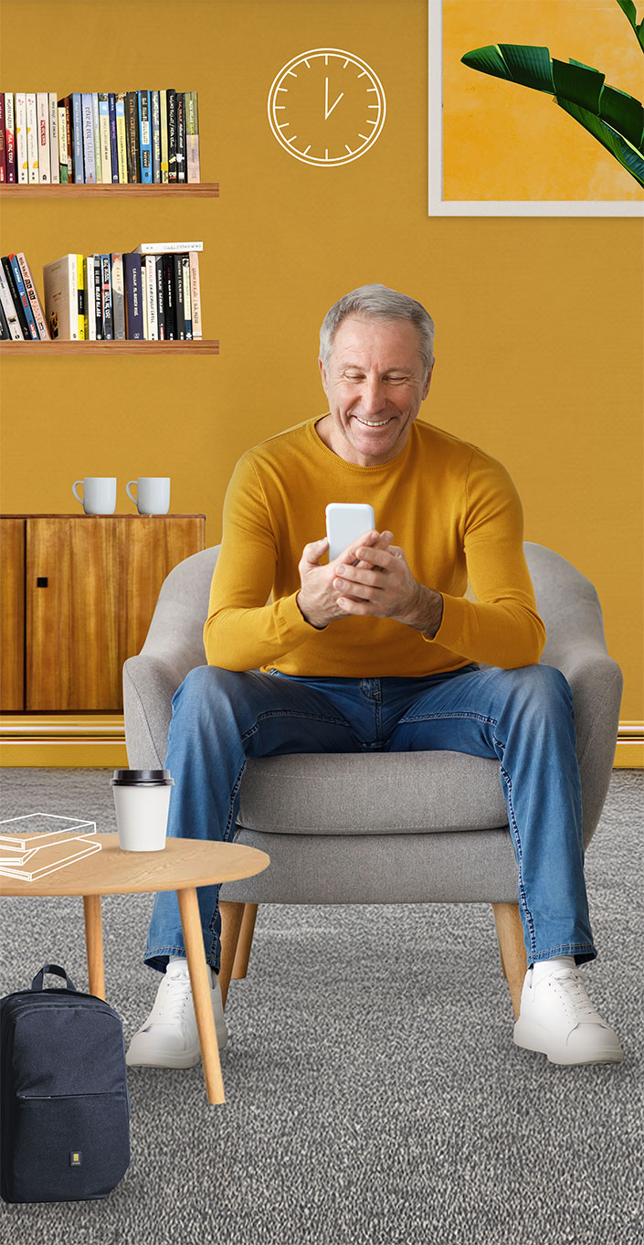 Homme assis confortablement dans un salon cosy, souriant en consultant son
téléphone